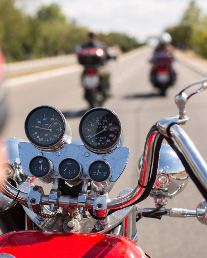 Biker riding motorcycle on road in morning sunny day. Shot from behind